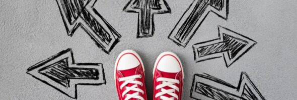 Feet in sneakers on the road with painted arrows pointing to different ways