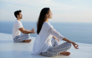 Young couple practicing yoga at sunset