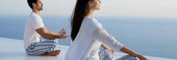 Young couple practicing yoga at sunset